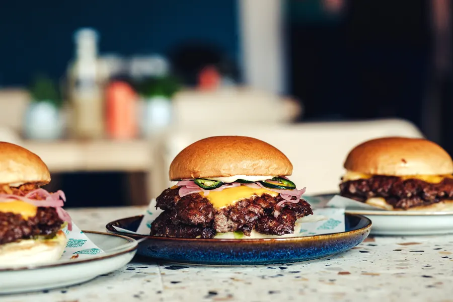 Three cheeseburgers lined up on the counter